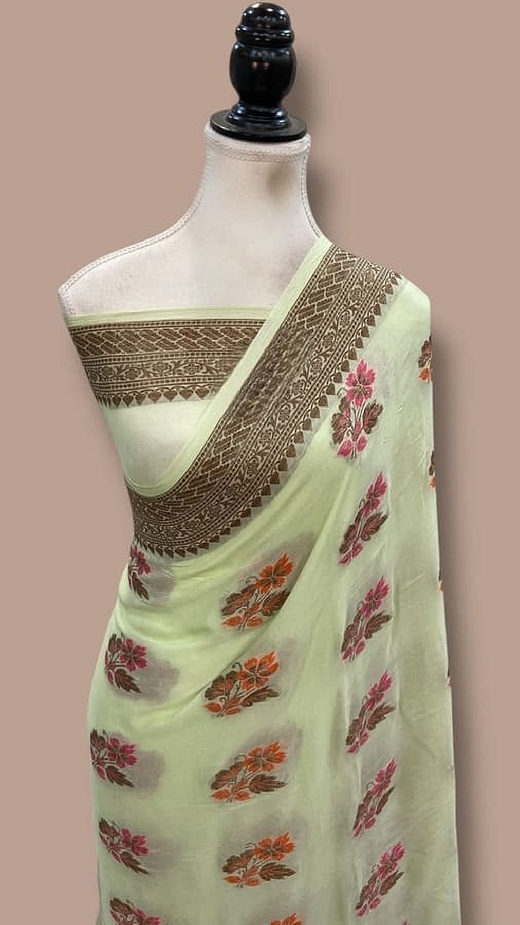 Mint green saree with gold-trimmed edge and red floral motifs, draped on mannequin