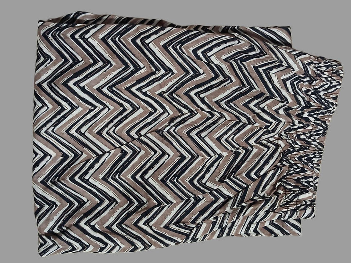 Chevron printed cotton fabric swatch in black and white with beige accents, folded
