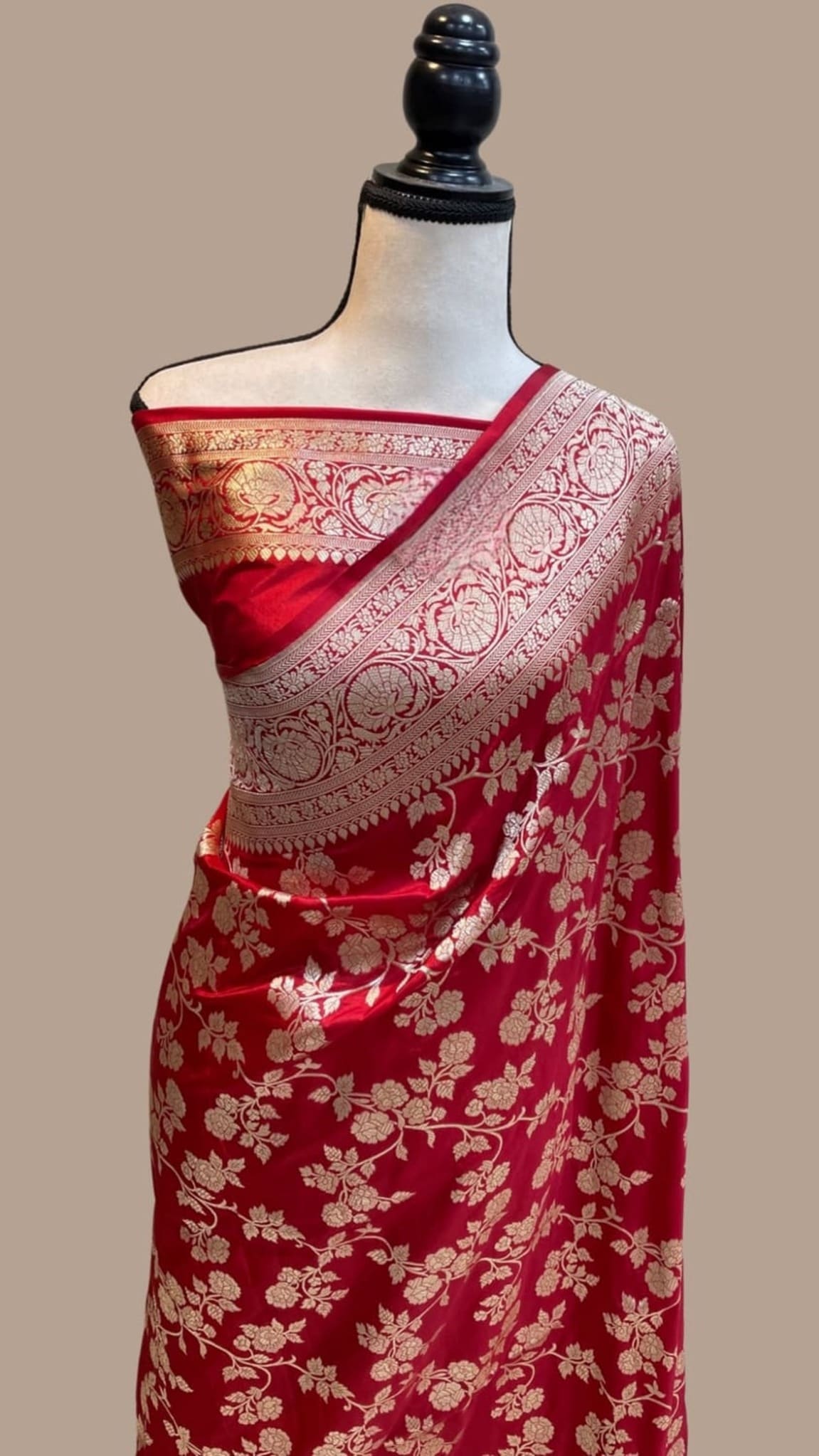 Red saree with wide gold zari pallu border and all-over floral jaal motifs, neatly draped.