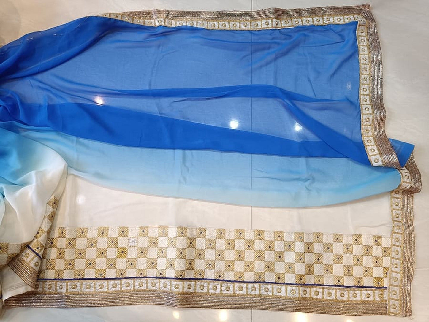 Light-to-mid blue saree with white pallu, gold border and checked trim band