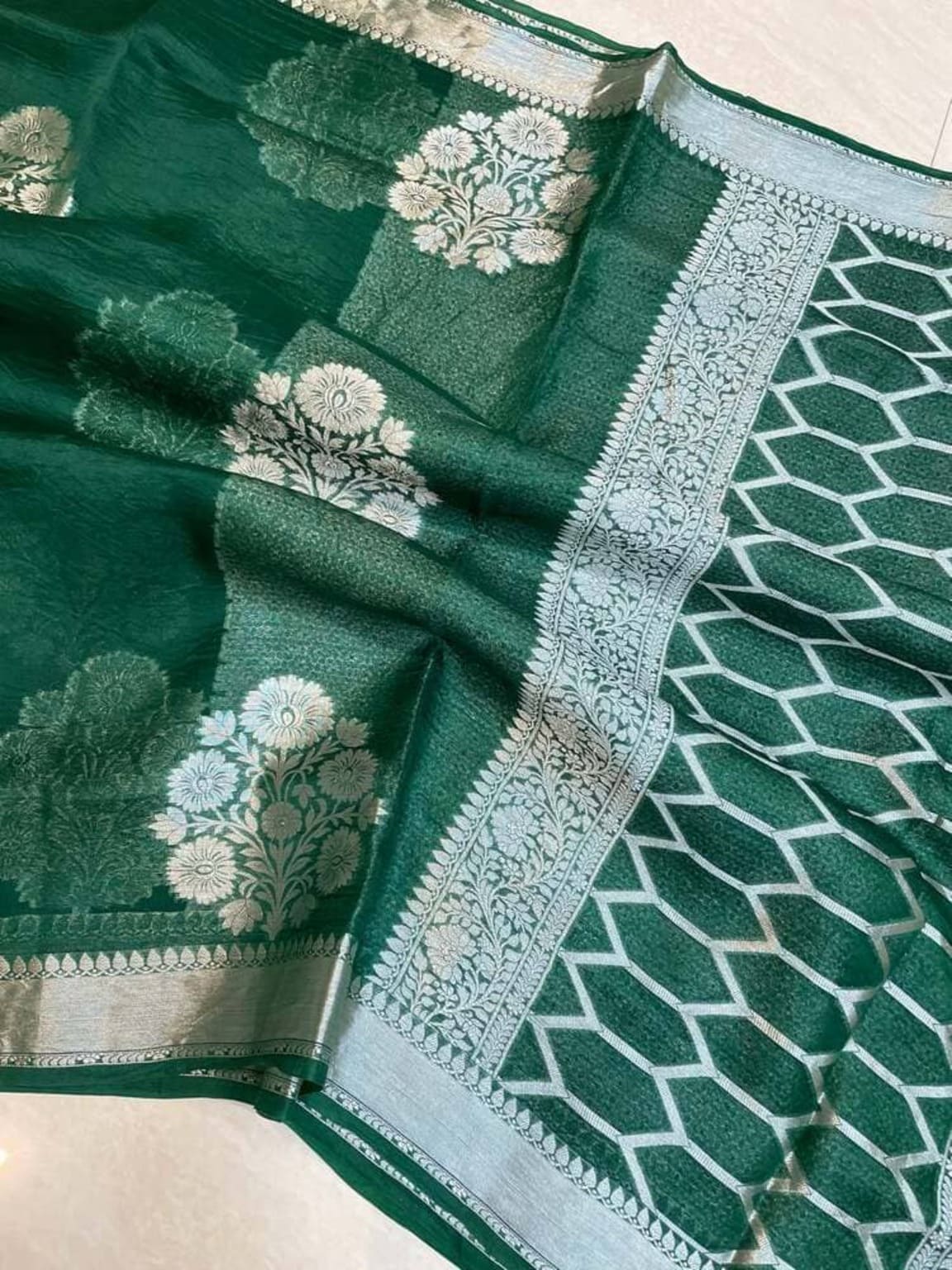 Dark green Banarasi saree with silver border and off-white lotus and mesh motifs