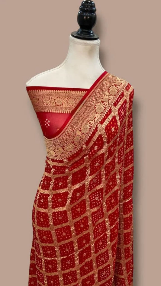 Red saree on mannequin with gold-toned border, bandhej dots and check pattern