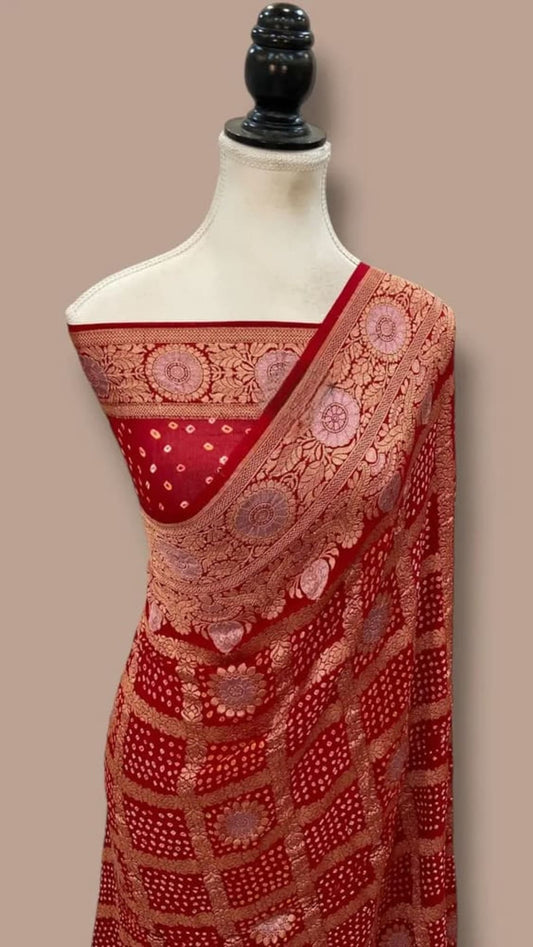 Red georgette-style saree drape with gold-toned woven border and circular motif accents