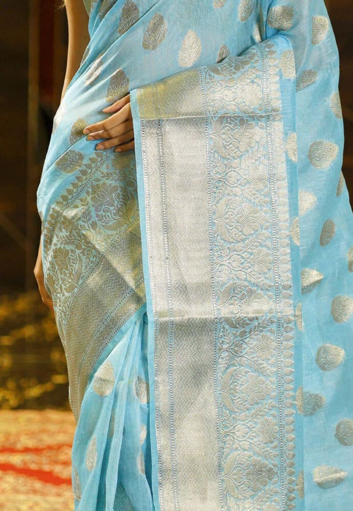 Aqua blue saree fabric detail with gold motifs and central silver zari panel