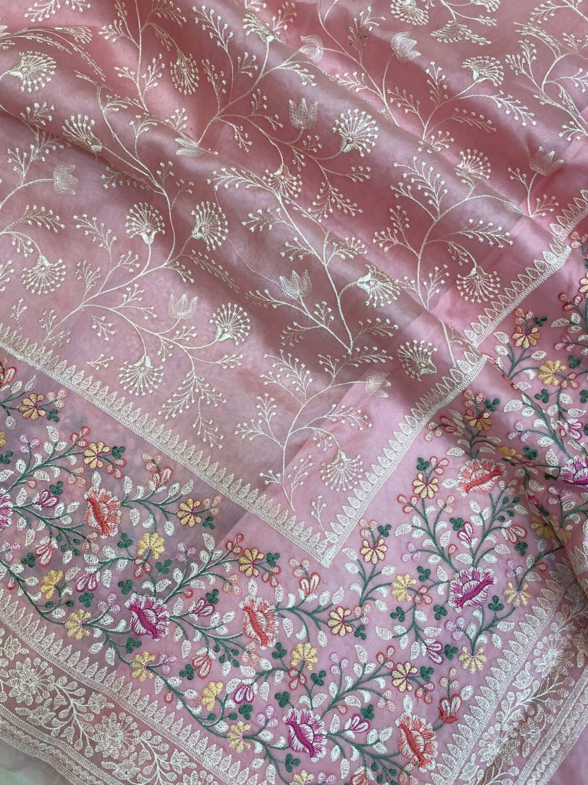 Pink organza pallu closeup with silver tree-and-flower vines, zari edge, and multicolor florals