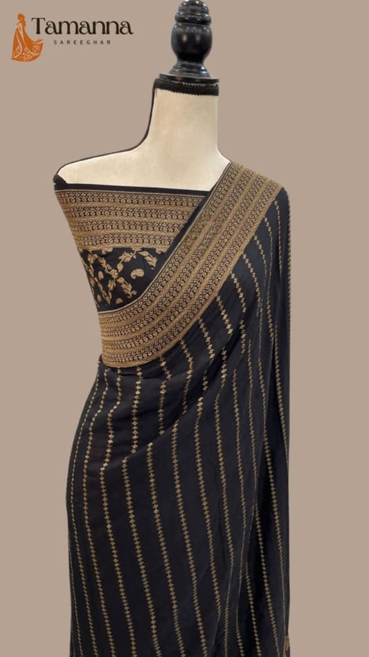Black saree draped on mannequin, gold zari diagonal border and striped body