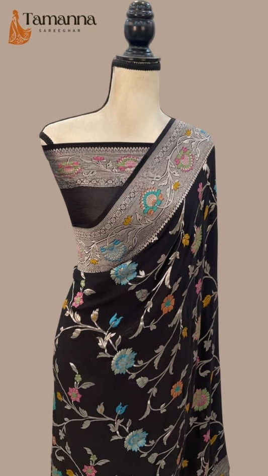 Black saree drape with colorful floral vines and detailed silver-gray pallu border