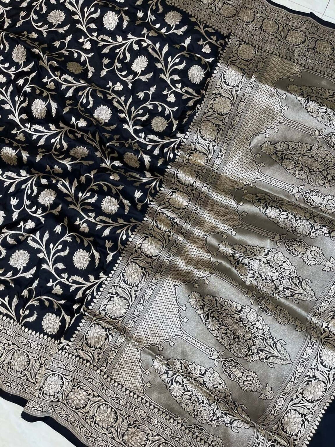Banarasi silk saree close-up of metallic silver panels with floral vines on dark fabric