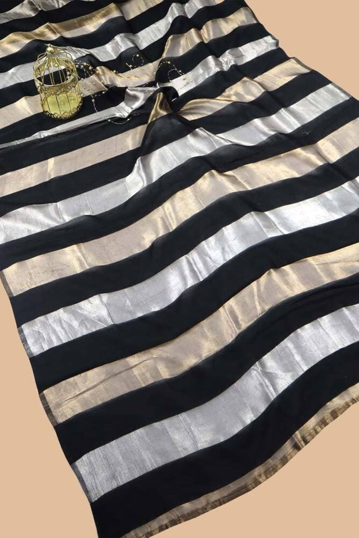 Folded saree showing black and silver stripes and gold border on fabric