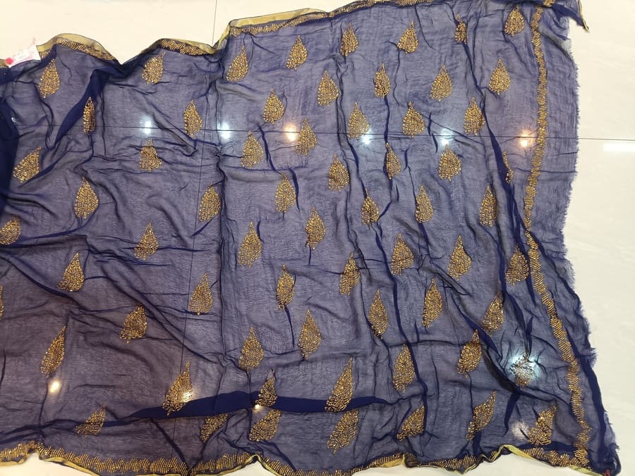 Blue chiffon saree close-up with ruched texture and scattered gold leaf motifs