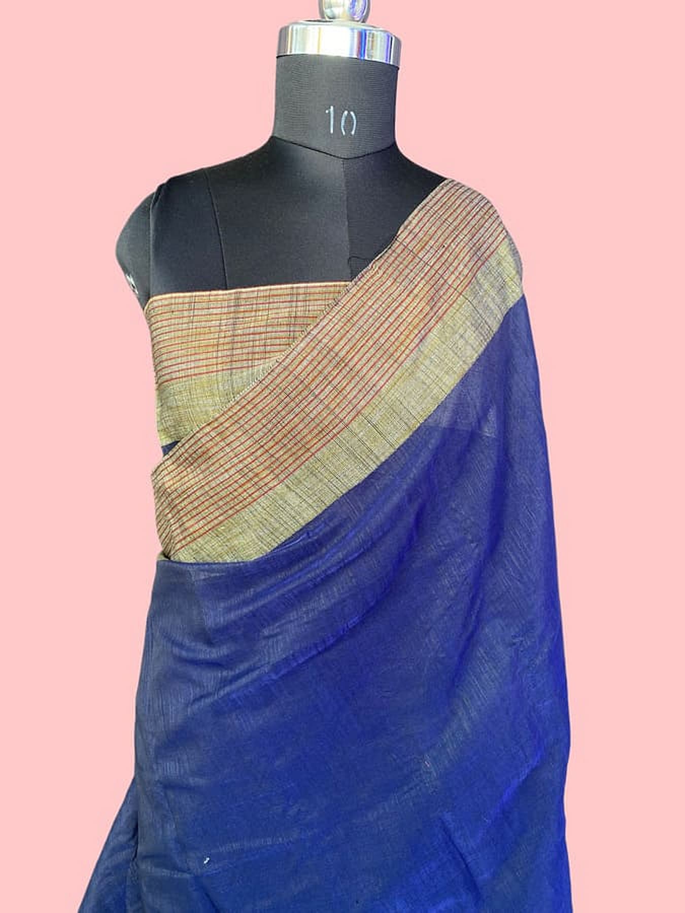 Blue silk saree on mannequin with diagonal beige-and-green striped border