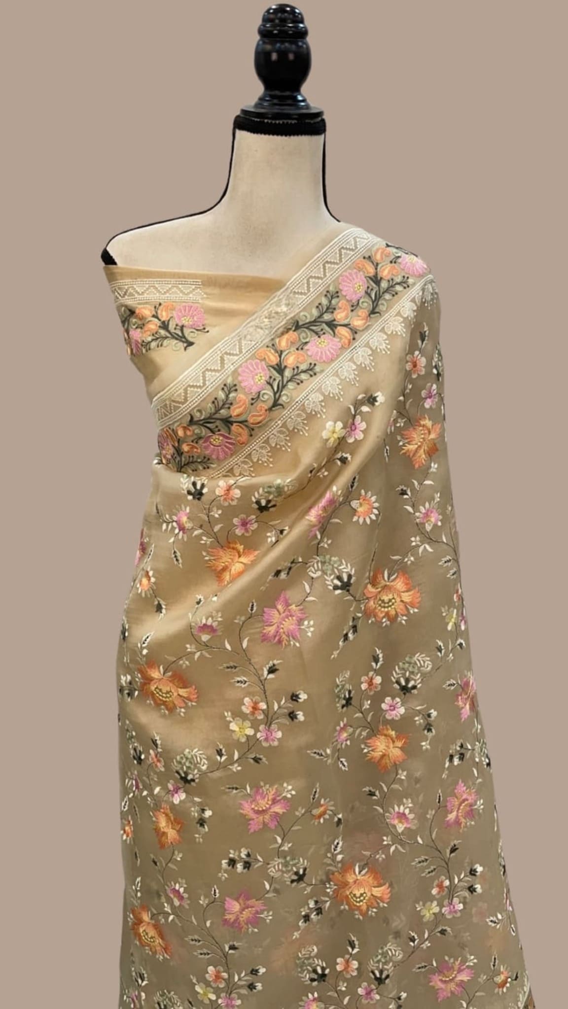 Beige organza saree with floral motif diagonal border, draped on mannequin