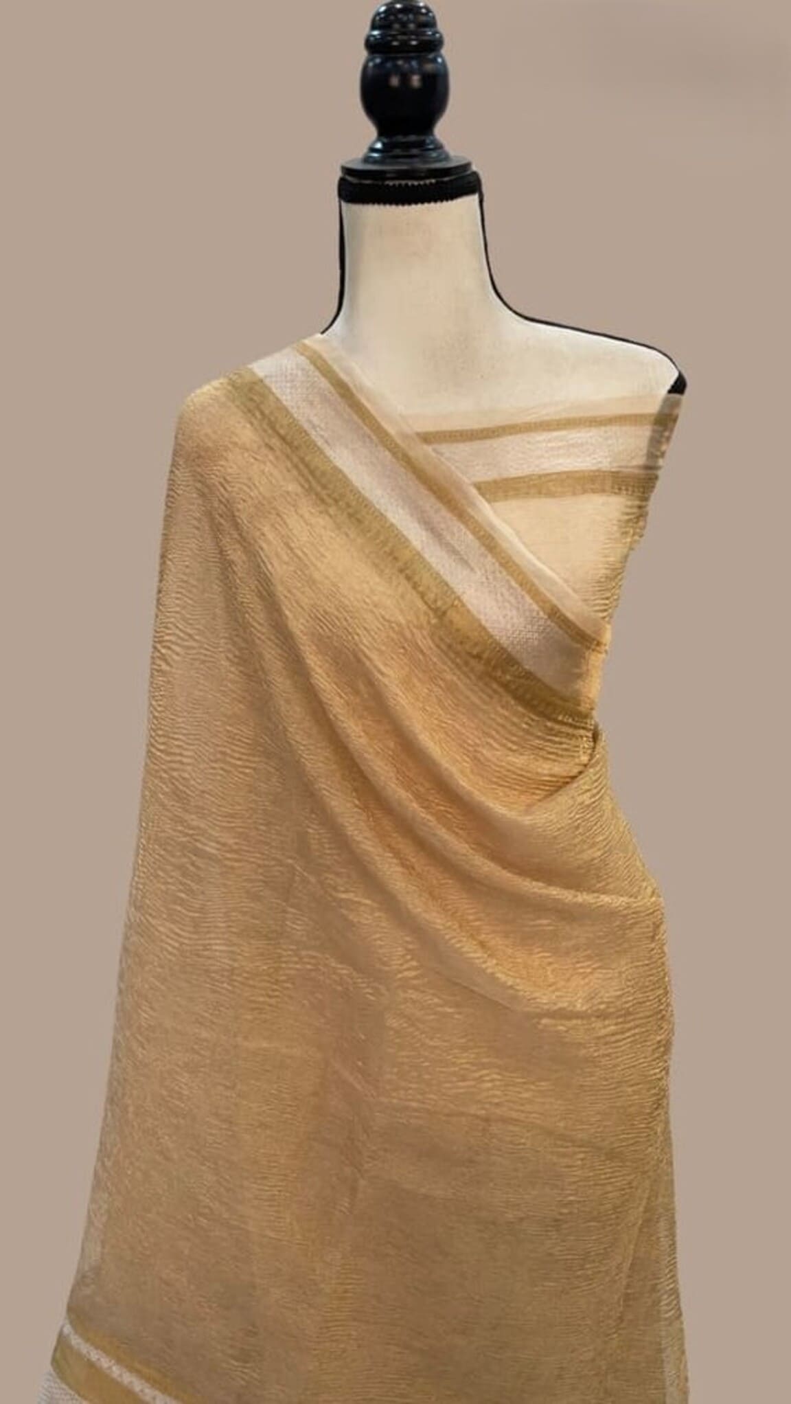 Cream tissue Banarasi saree with gold zari pallu and border, draped on mannequin