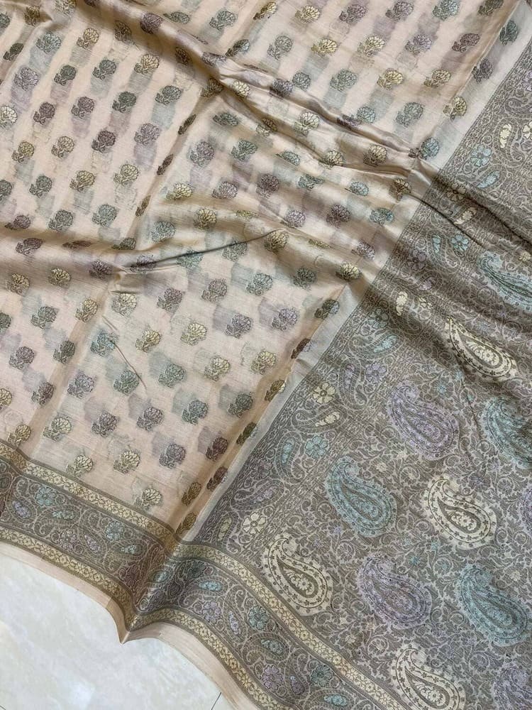 Off-white butter saree fabric close-up with small motifs and ornate paisley border