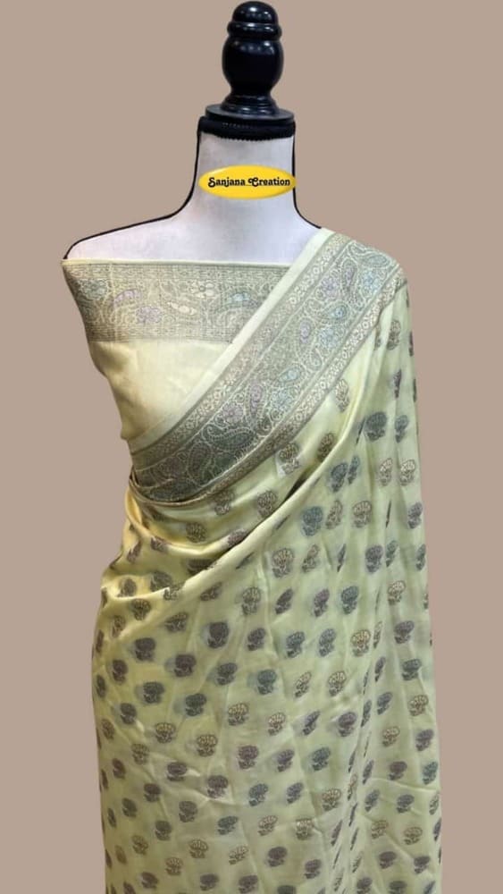 Off-white butter crepe Banarasi saree with teal and gold border, draped on mannequin