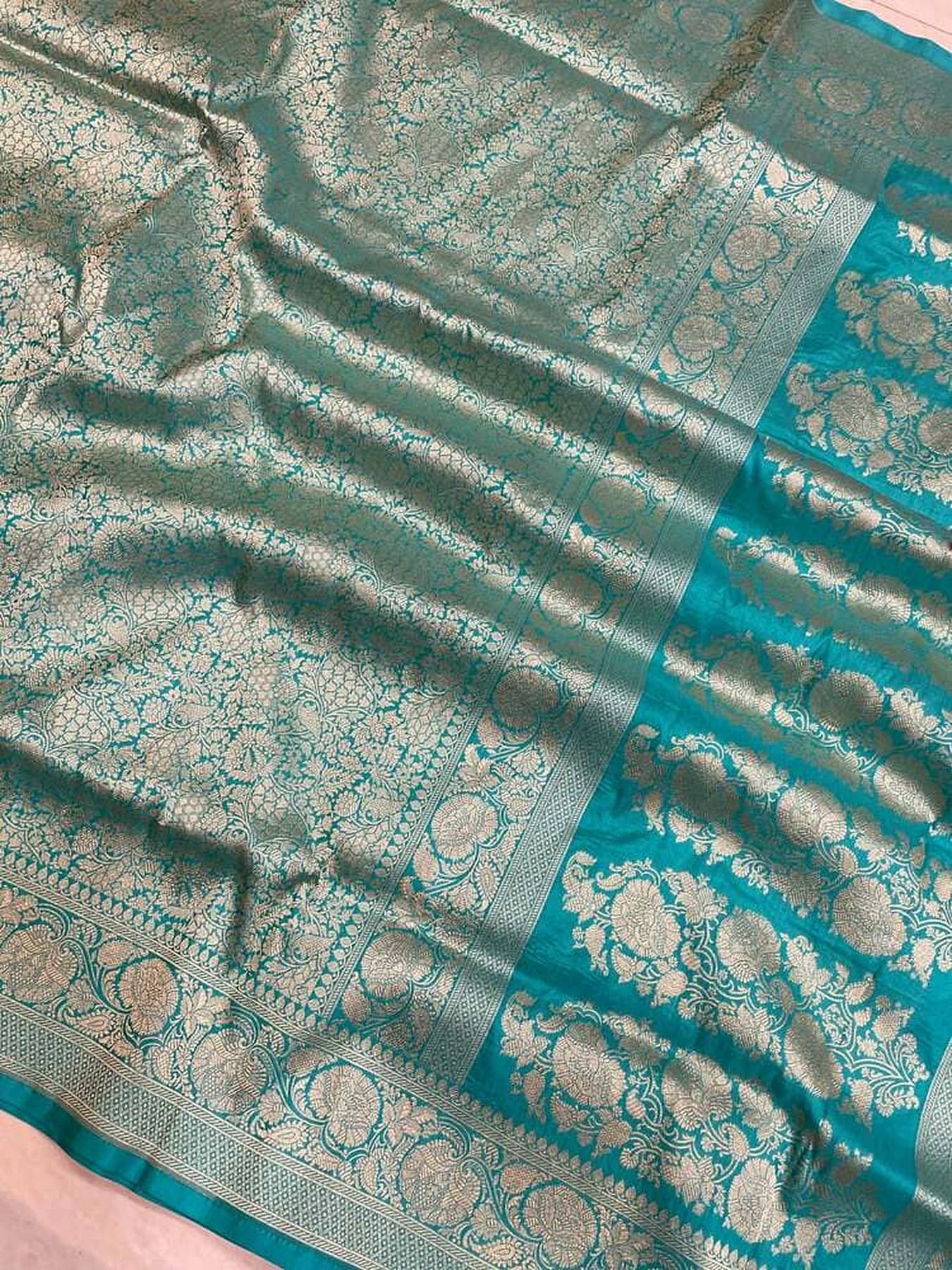 Close-up of teal silk saree with gold brocade weave and teal contrasting border