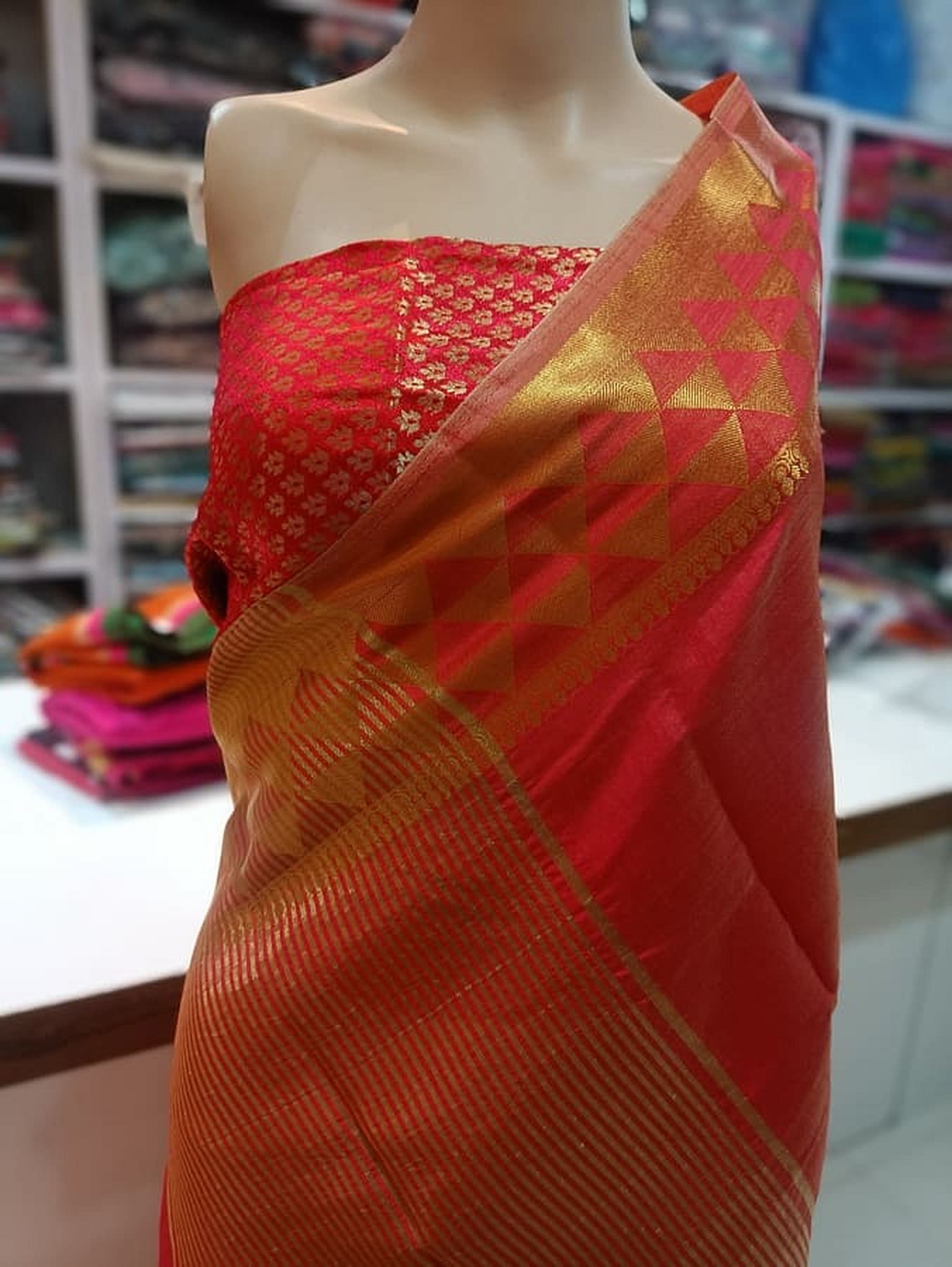 Gold pallu with triangle motifs and red patterned silk saree draped on mannequin