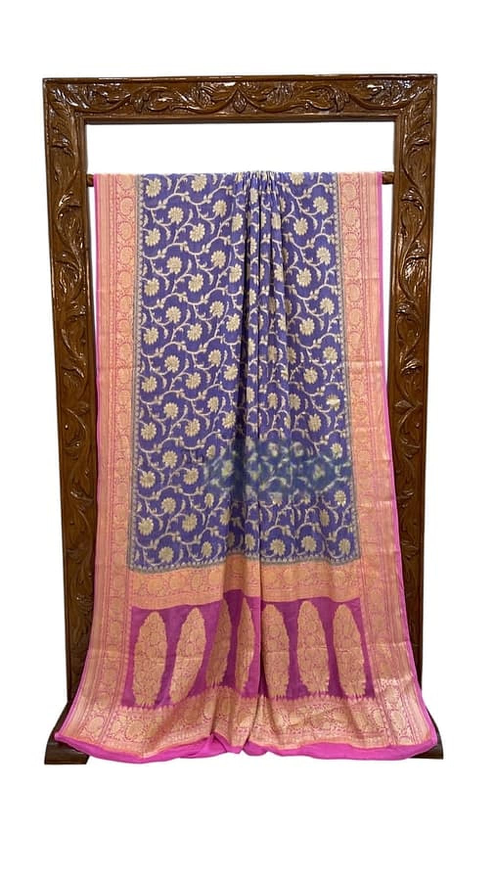 Blue saree with gold motifs, wide pink border and fringed hem, displayed hanging
