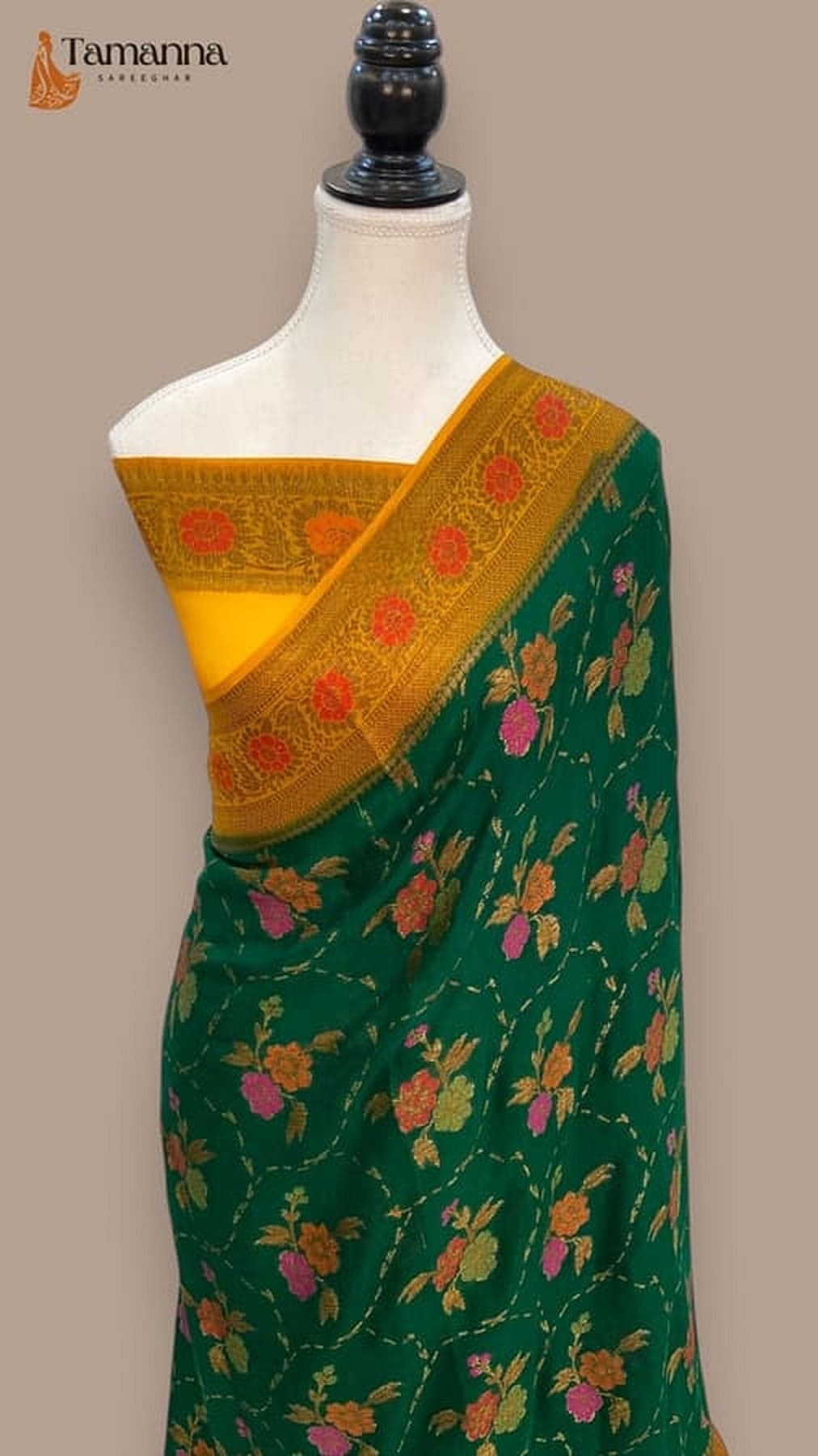 Dark green saree with mustard-gold border and dense orange floral motifs, draped on mannequin