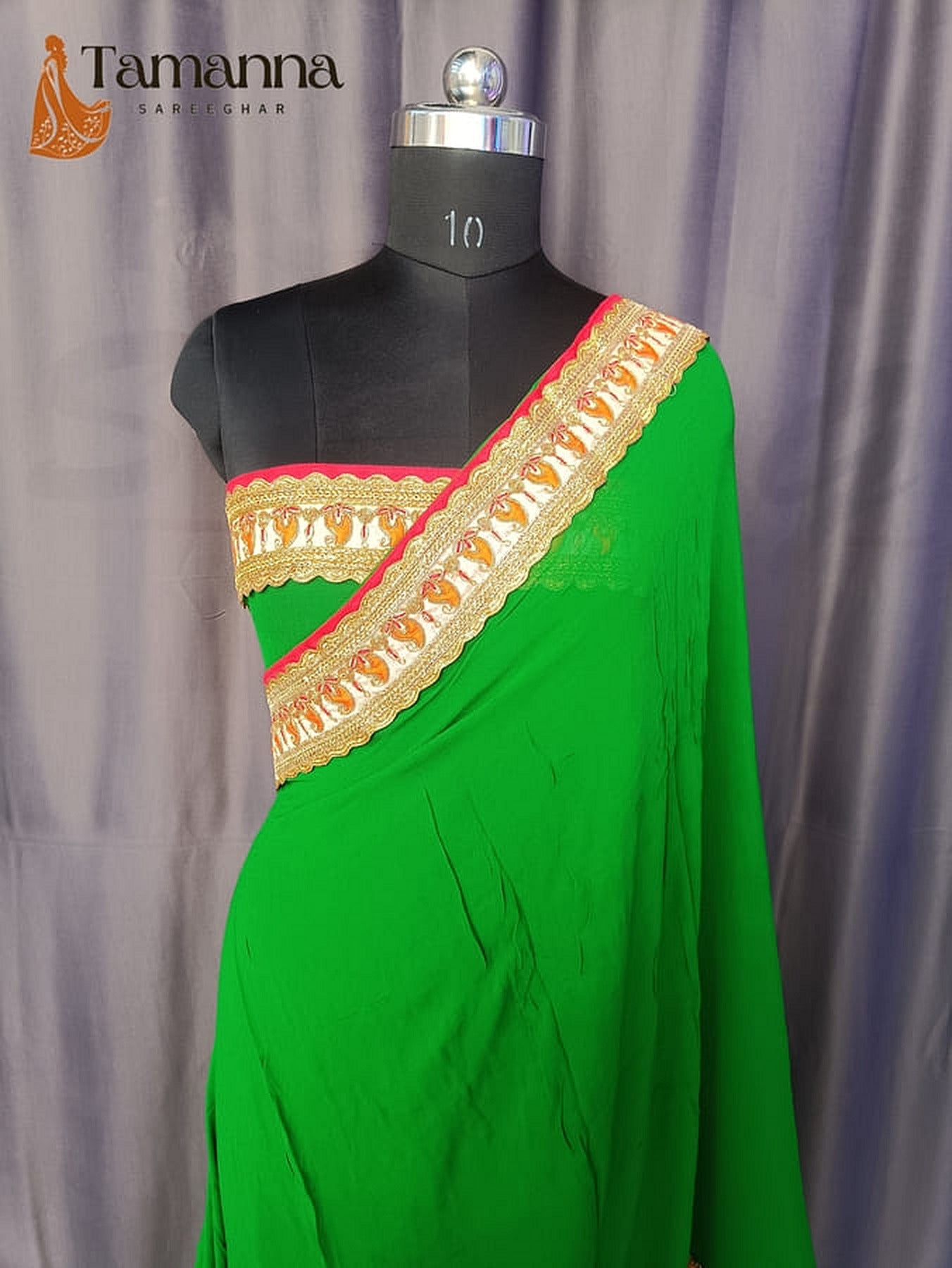 Green saree with gold and red border, single-shoulder drape on mannequin