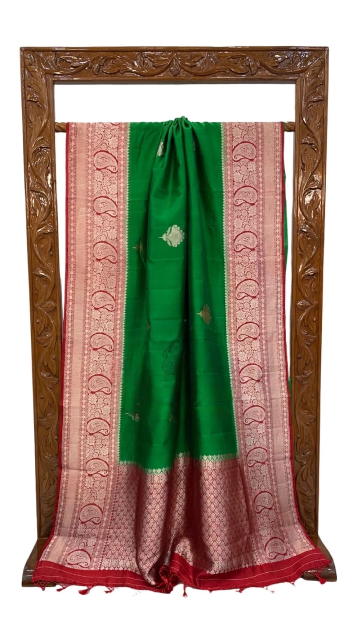 Green silk saree hanging display, pink patterned pallu panels, gold motif accents along border