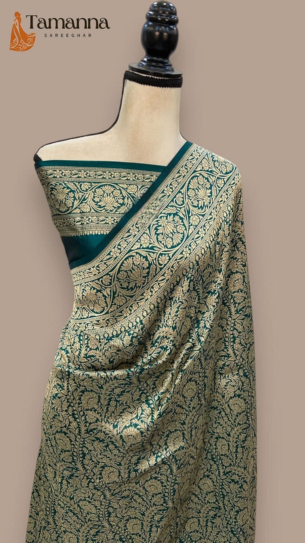 Teal-green silk saree with gold vine motifs and contrast border, shown on mannequin