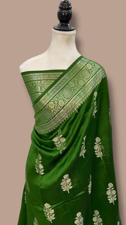 Green silk saree draped on mannequin with gold border and scattered floral motifs