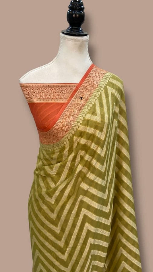 Draped olive-green saree with zigzag print, orange pallu, and ornate gold border