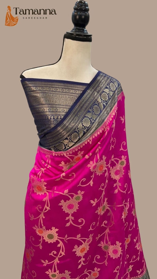 Hot pink silk saree draped on mannequin with navy border and gold vine motifs