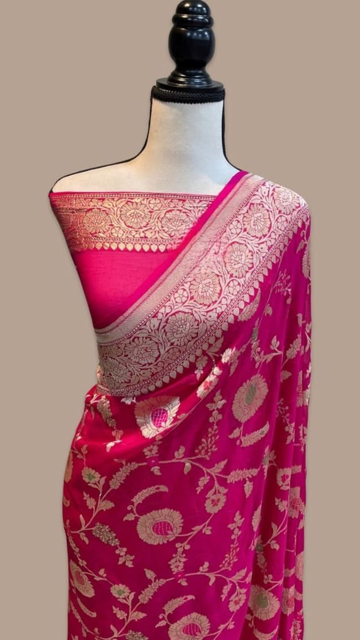 Hot pink saree draped on mannequin with wide silver-gold embellished border