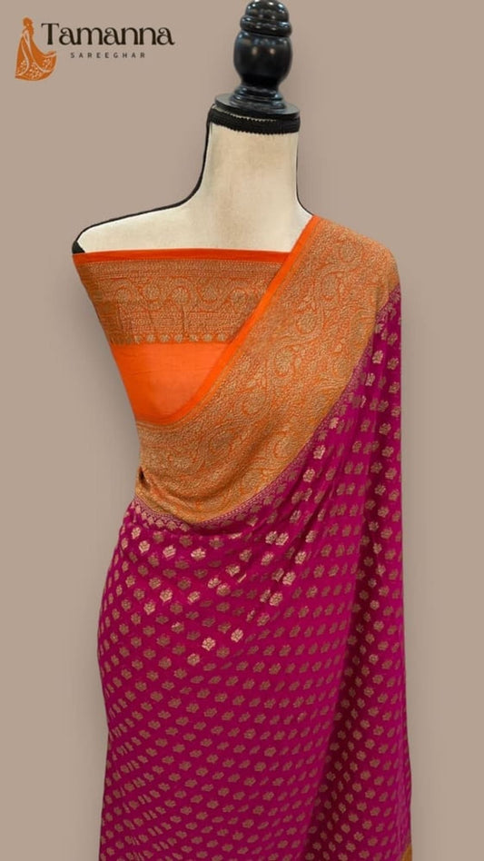 Hot pink sari with orange-gold pallu border over shoulder, woven motifs visible.