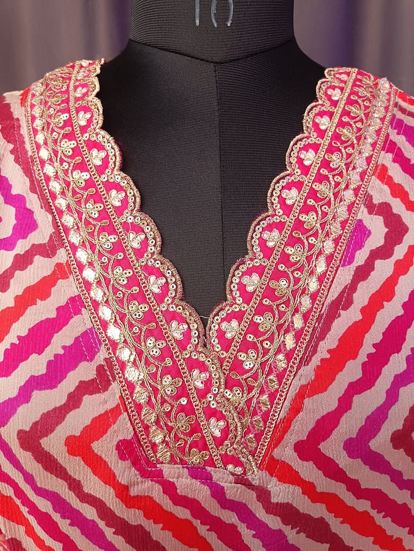 Hot pink kurta neckline with heavy gold sequin work and V-shaped embroidered border
