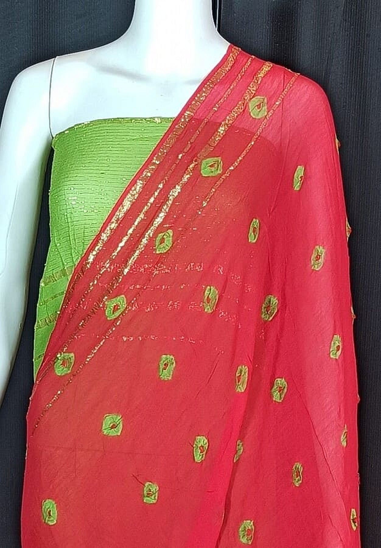 Hot pink bandhani saree with scattered green motif dots and gold striped border on drape