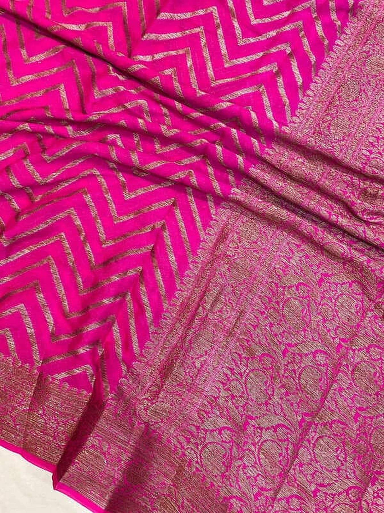 Hot pink chiffon saree close-up with gold zigzag motifs and ornate zari border