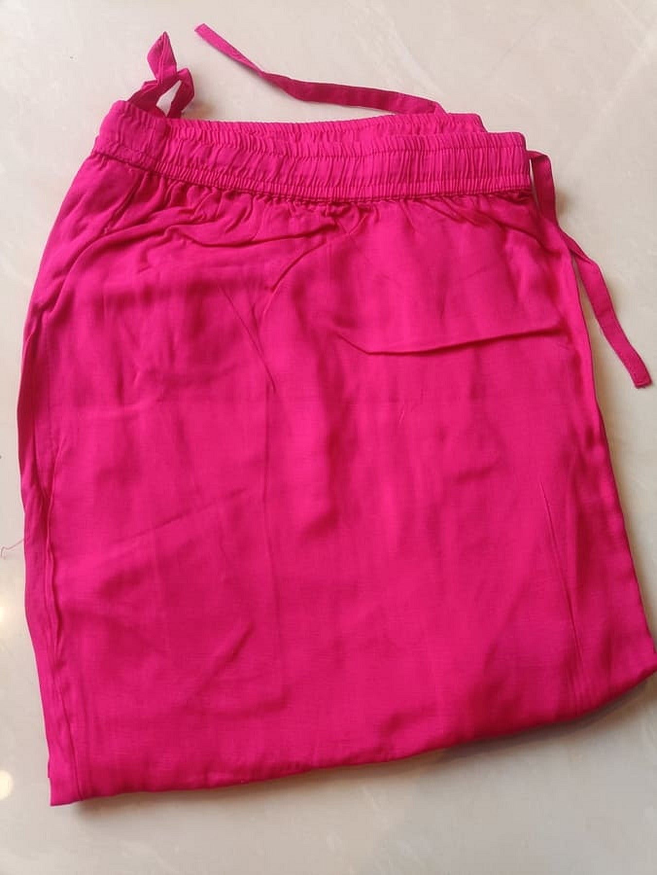 Hot pink drawstring pants with elastic waistband and tied string at side