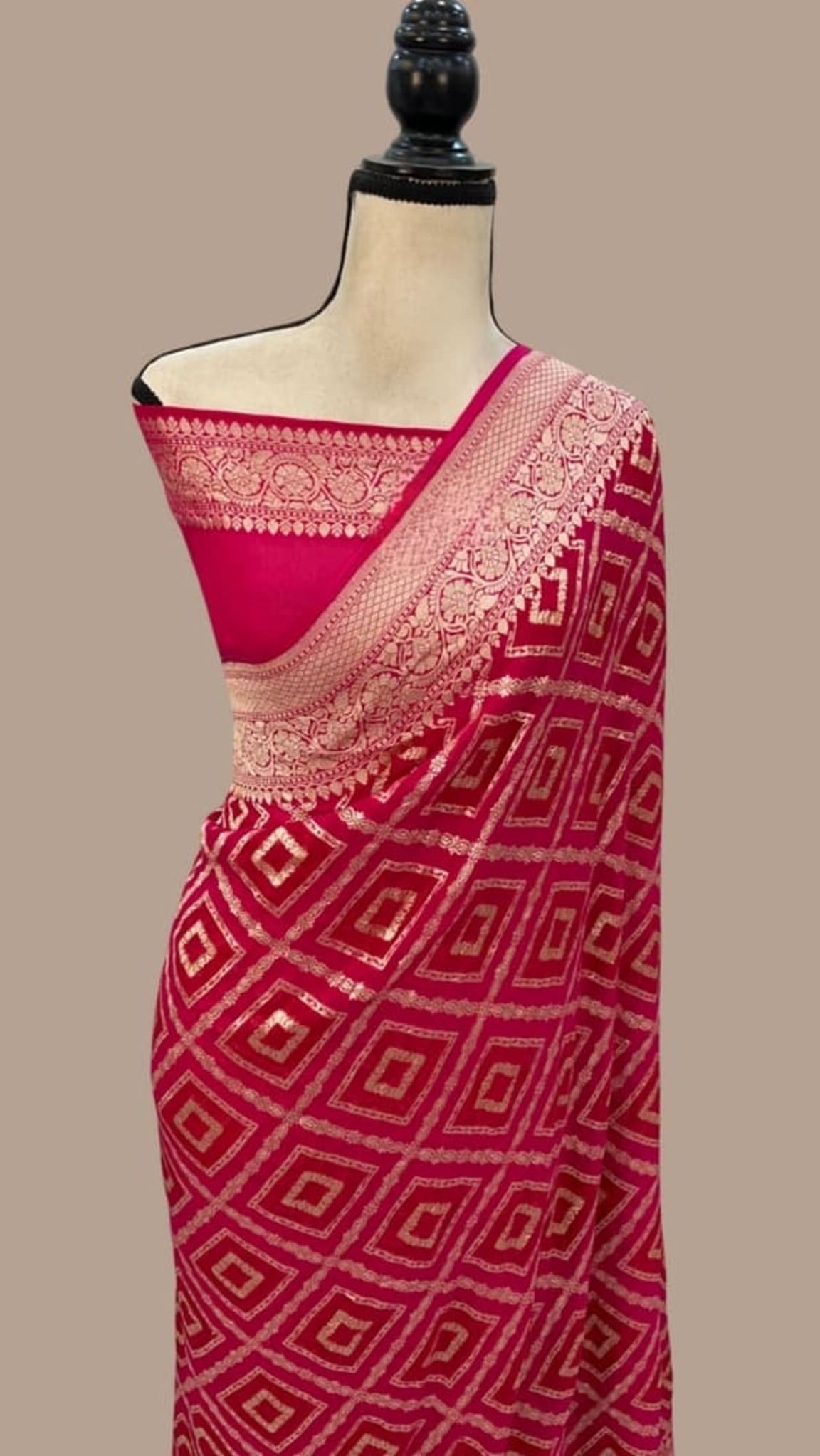 Hot pink saree with beige-gold border and geometric motifs, draped on mannequin