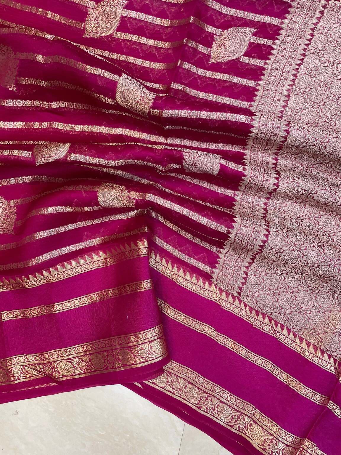 Hot pink Banarasi saree with gold zari stripes and detailed floral border on the pallu