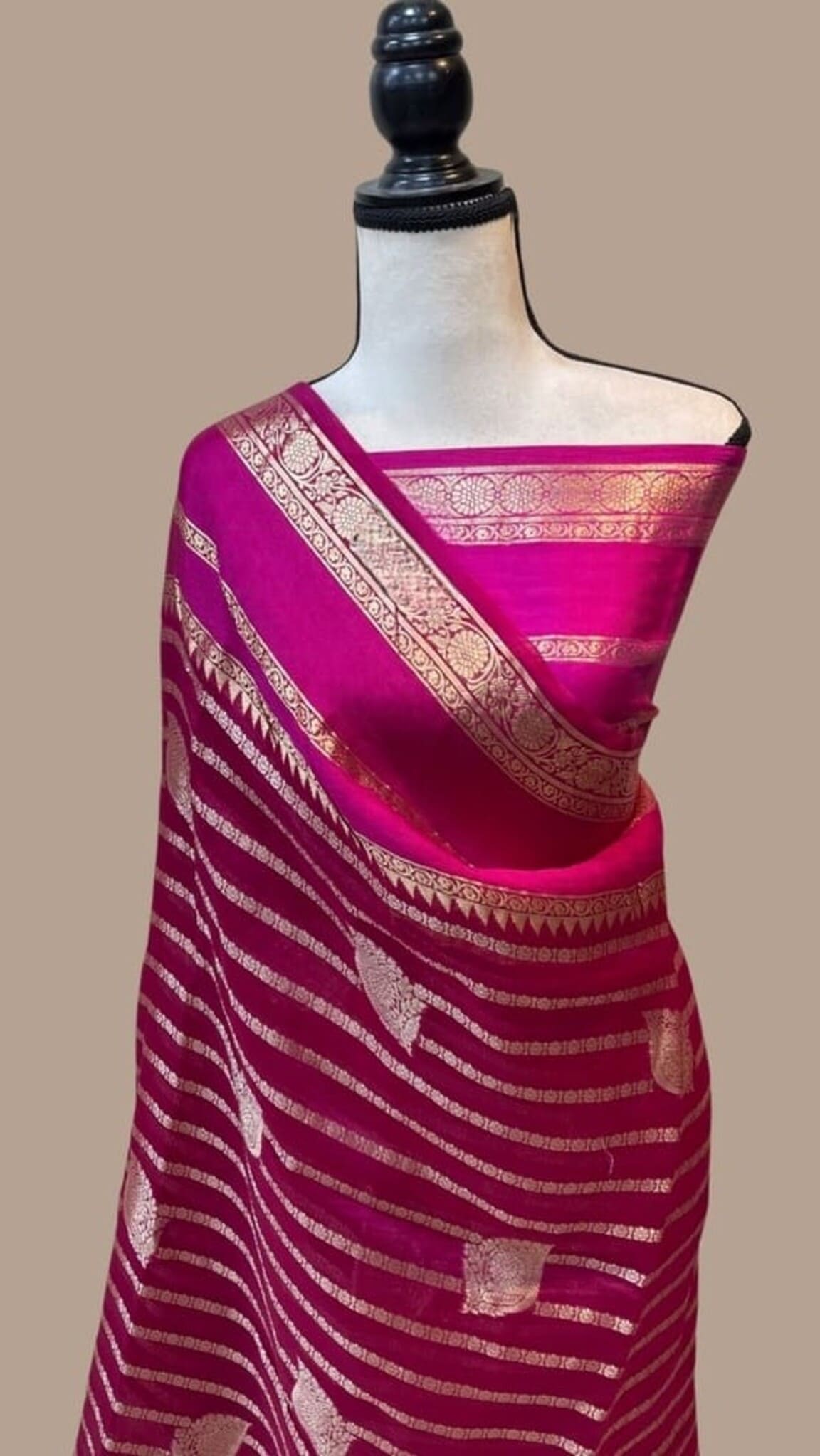 Hot pink Banarasi saree draped on mannequin, gold zari border and striped pattern