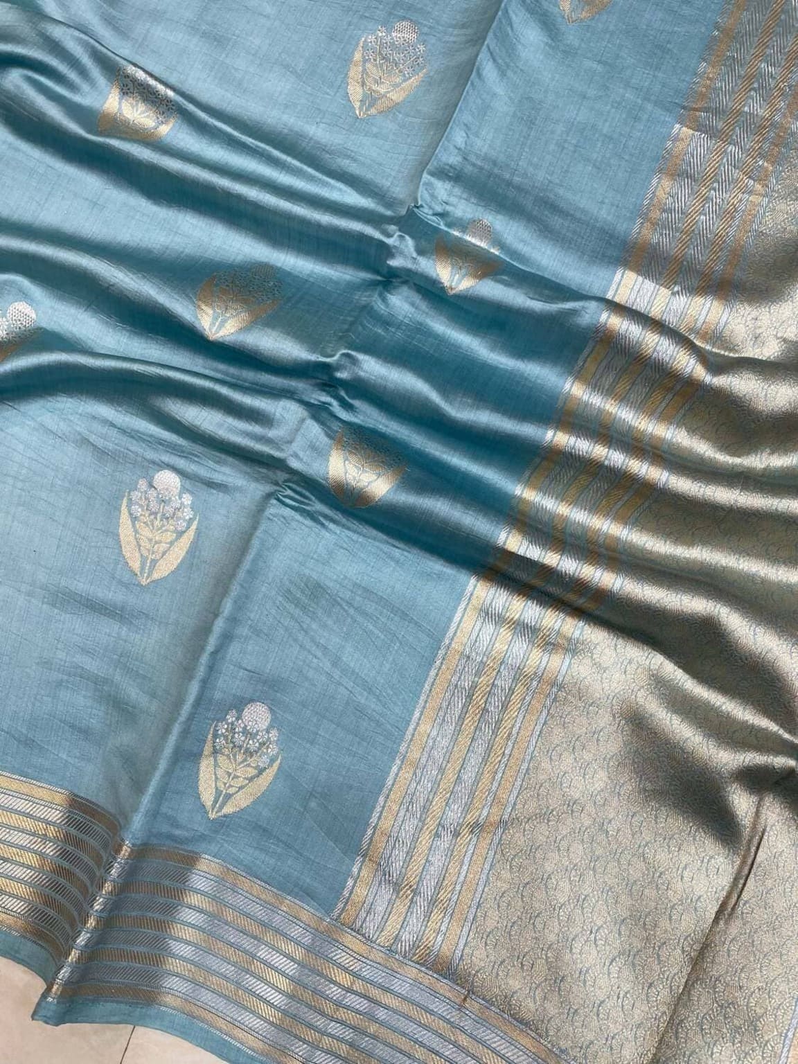 Close-up of ice blue silk with gold leaf motifs and textured zari stripes