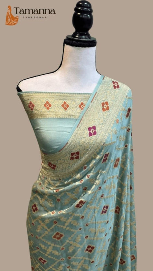 Ice blue georgette saree with gold zari waistband and red floral meenakari work