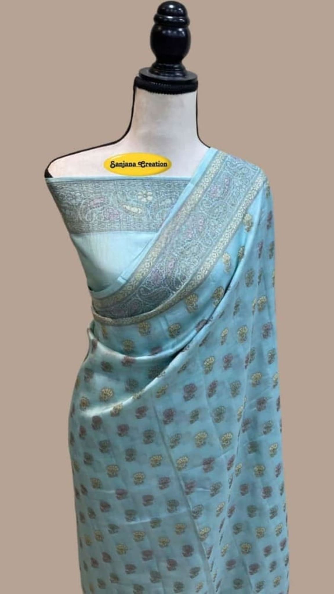 Ice blue Banarasi saree with repeating gold motifs and grey zari border on draped fabric