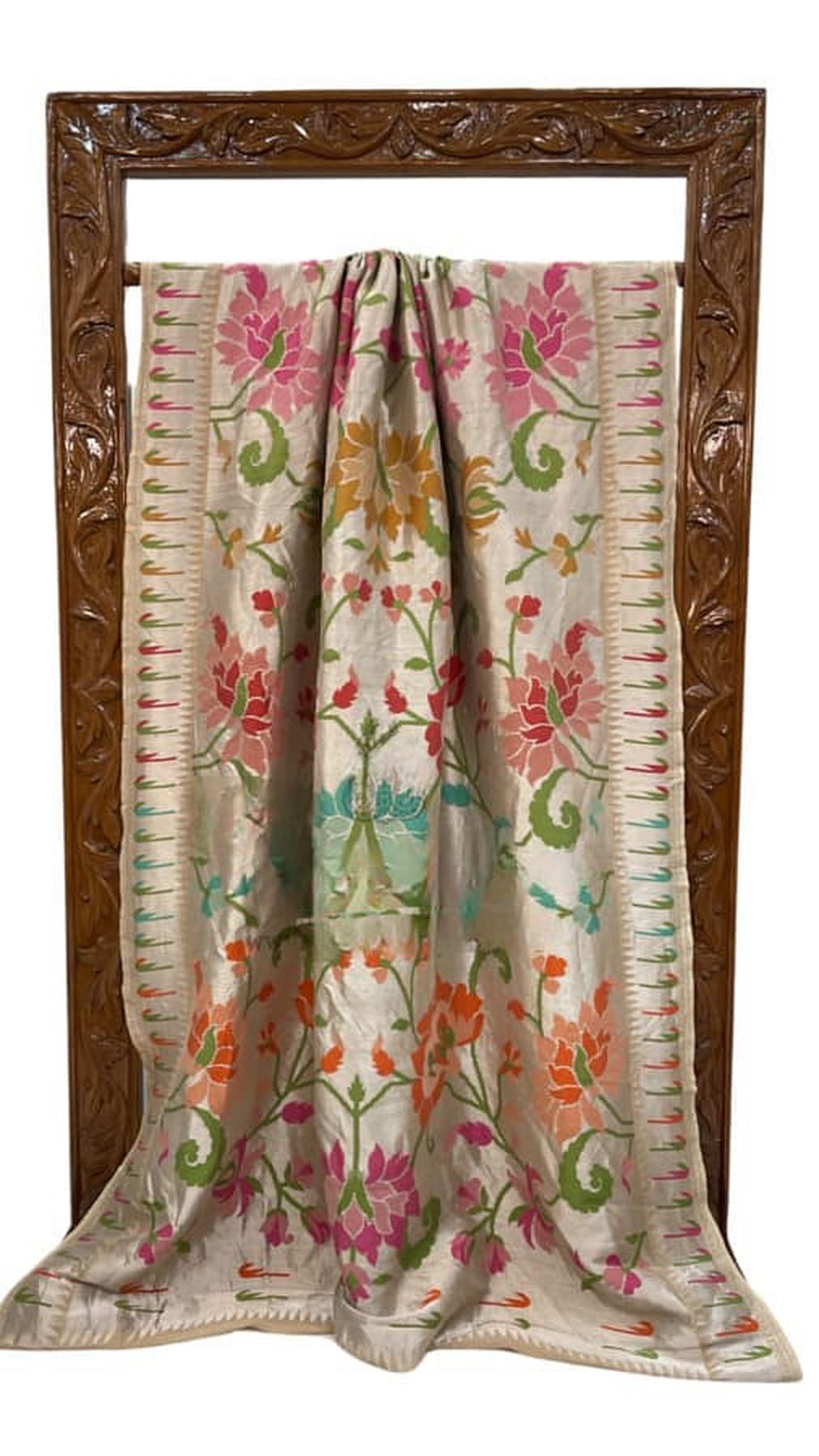 Ivory saree spread on stand with colorful floral pattern and striped border