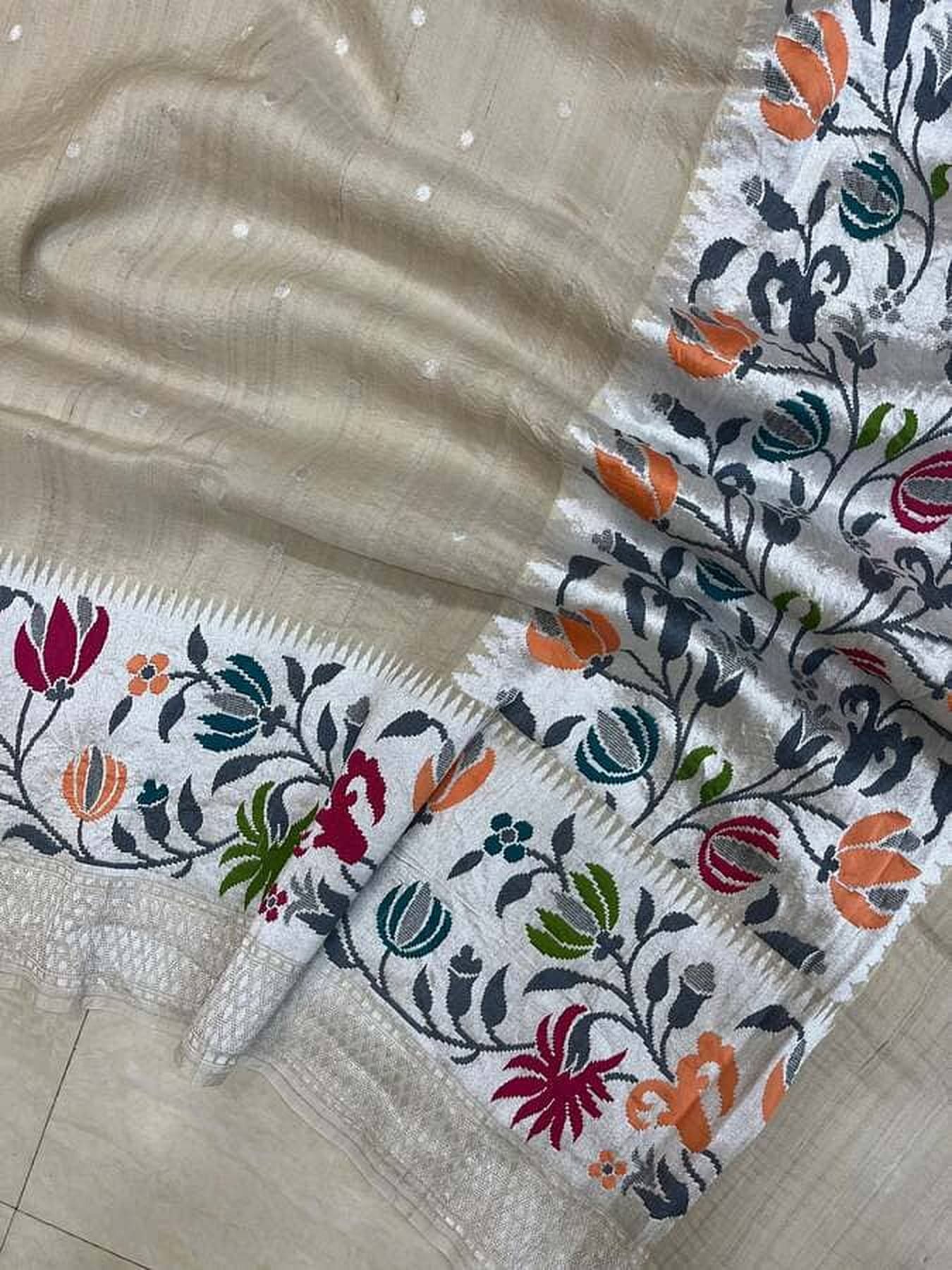 Ivory saree border detail with folk floral prints in orange, teal, and pink on black