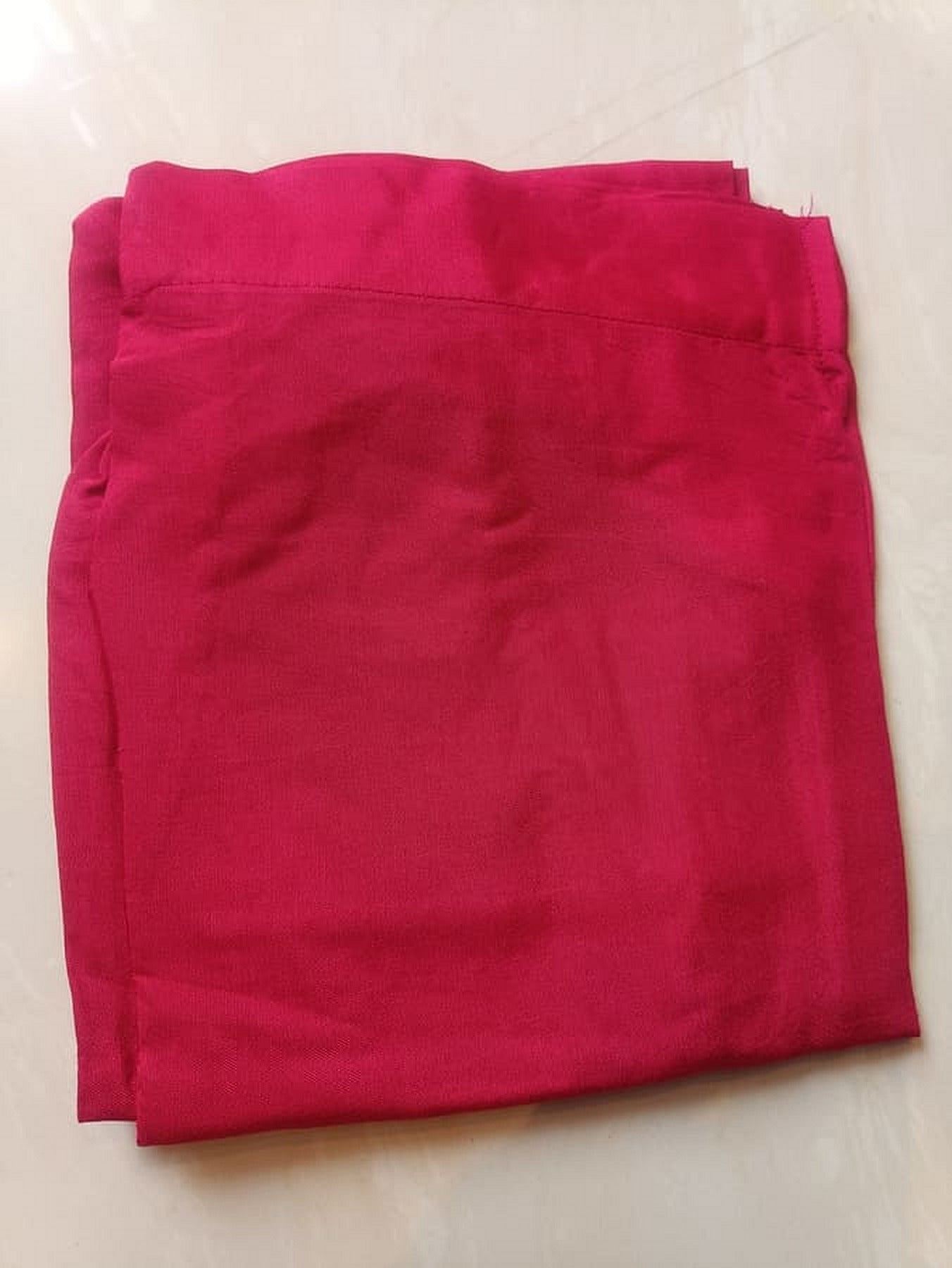 Hot pink straight suit bottoms folded, solid fabric with straight edges