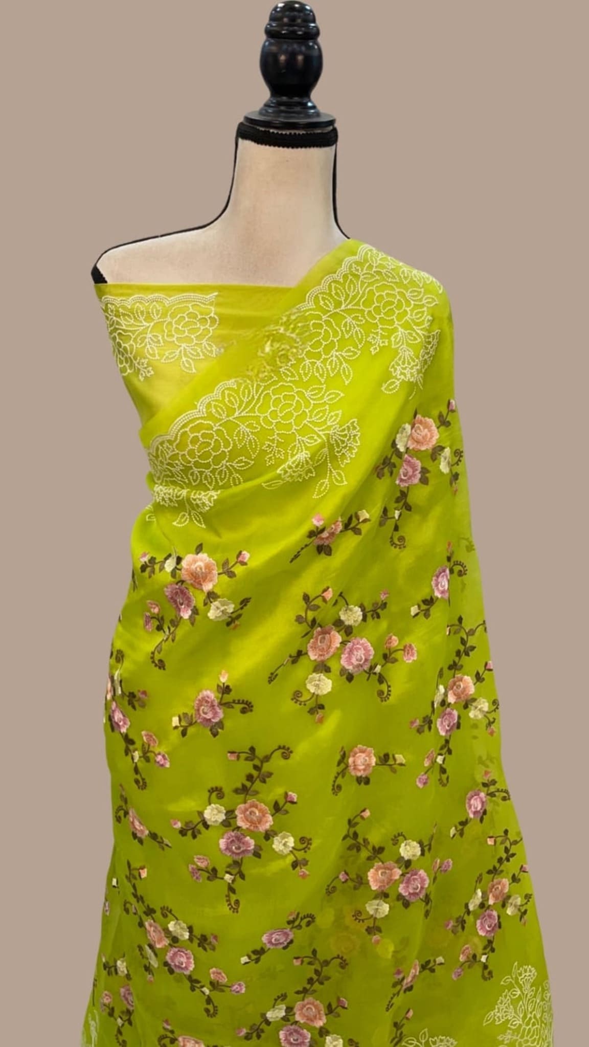 Lime yellow organza saree on mannequin with white floral jaal border and pink roses