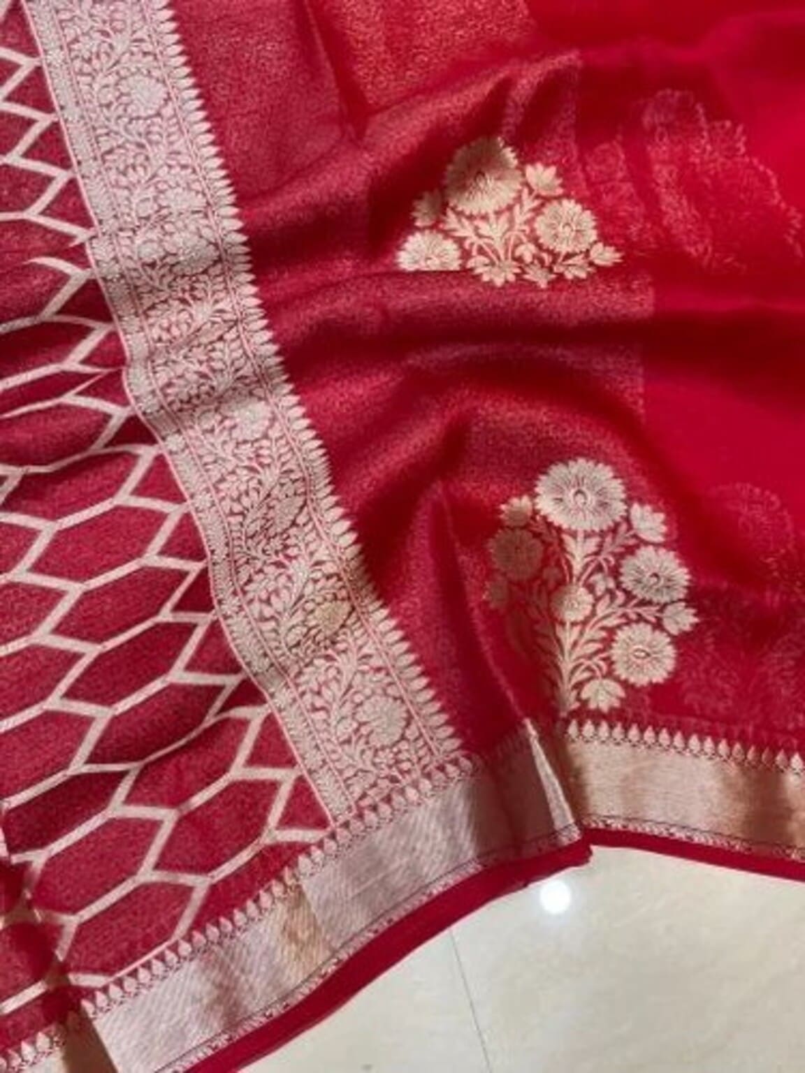 Red saree with ornate silver-gold border and floral motifs on pallu