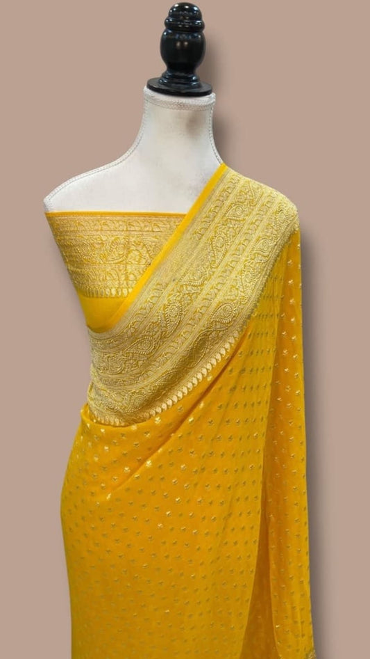 Yellow saree with gold patterned pallu and zari-edged border on mannequin