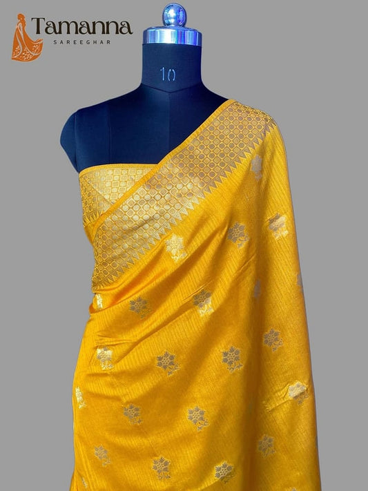Yellow silk saree with gold zari pallu border and scattered motifs, one-shoulder drape.