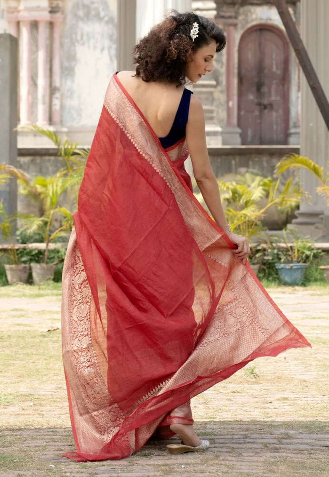 Maroon saree seen from back, beige-gold pallu border and flowing drape