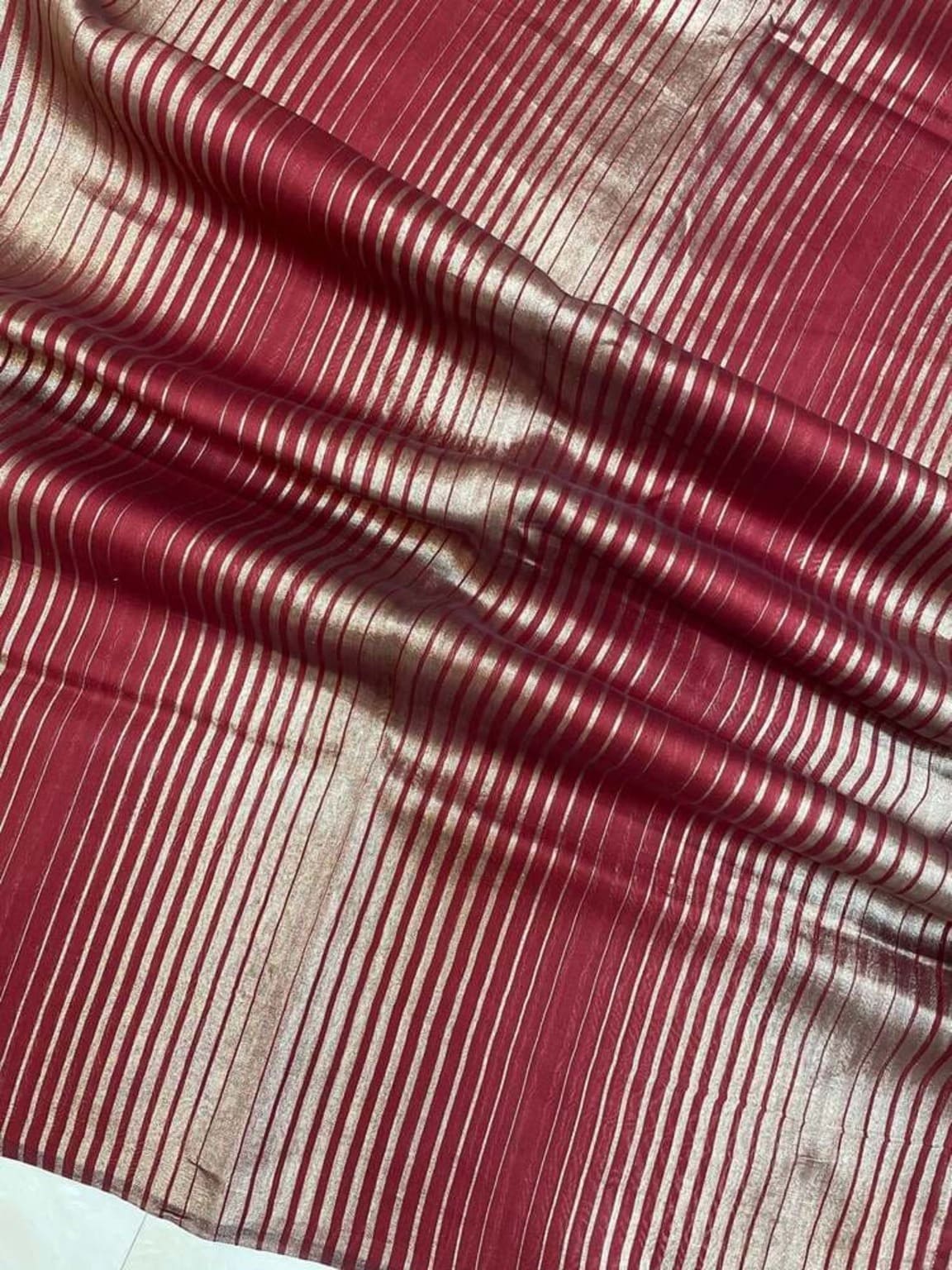 Maroon saree close-up showing vertical gold zari stripes on tissue weave